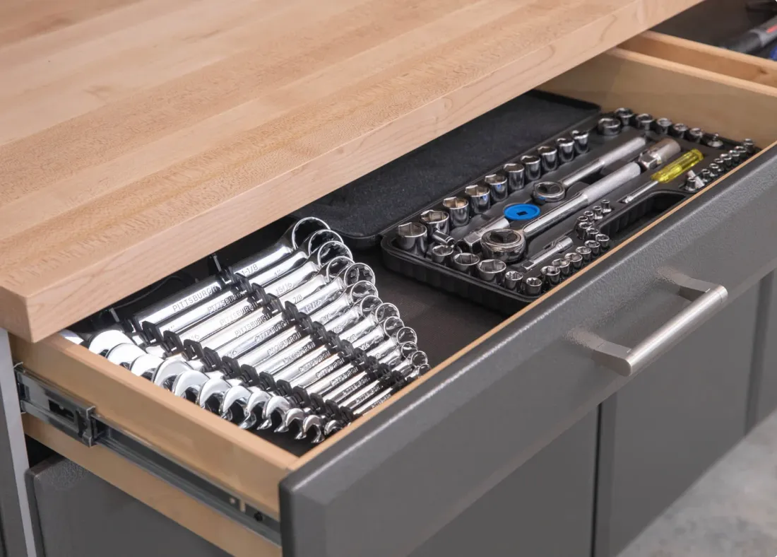 Open graphite cabinet drawer with organized tools, wood drawer construction and a butcher-block worktop